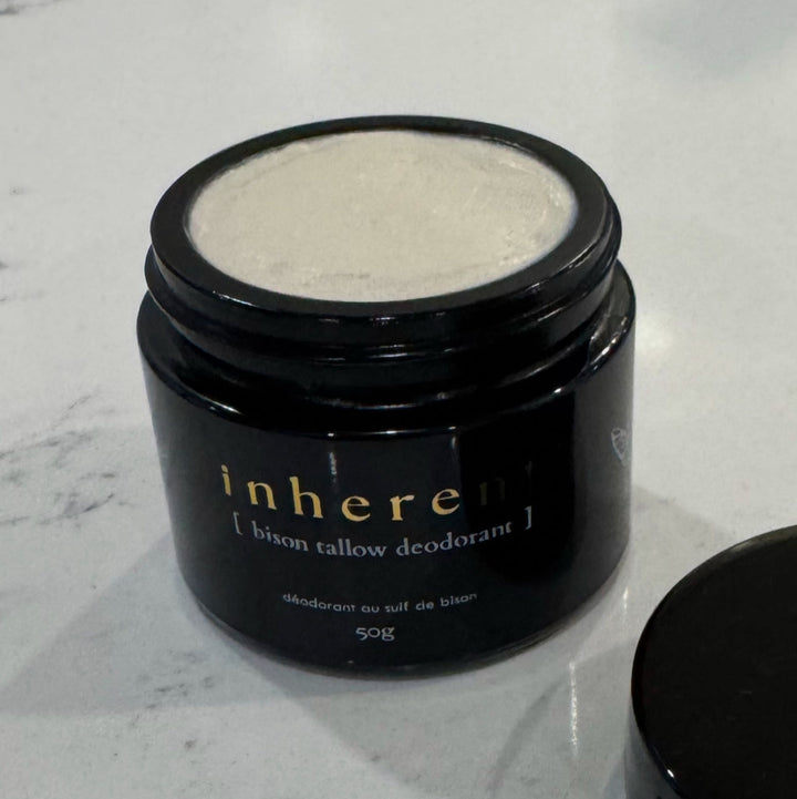 Black jar of 'inhere' bison tallow deodorant on a marble surface